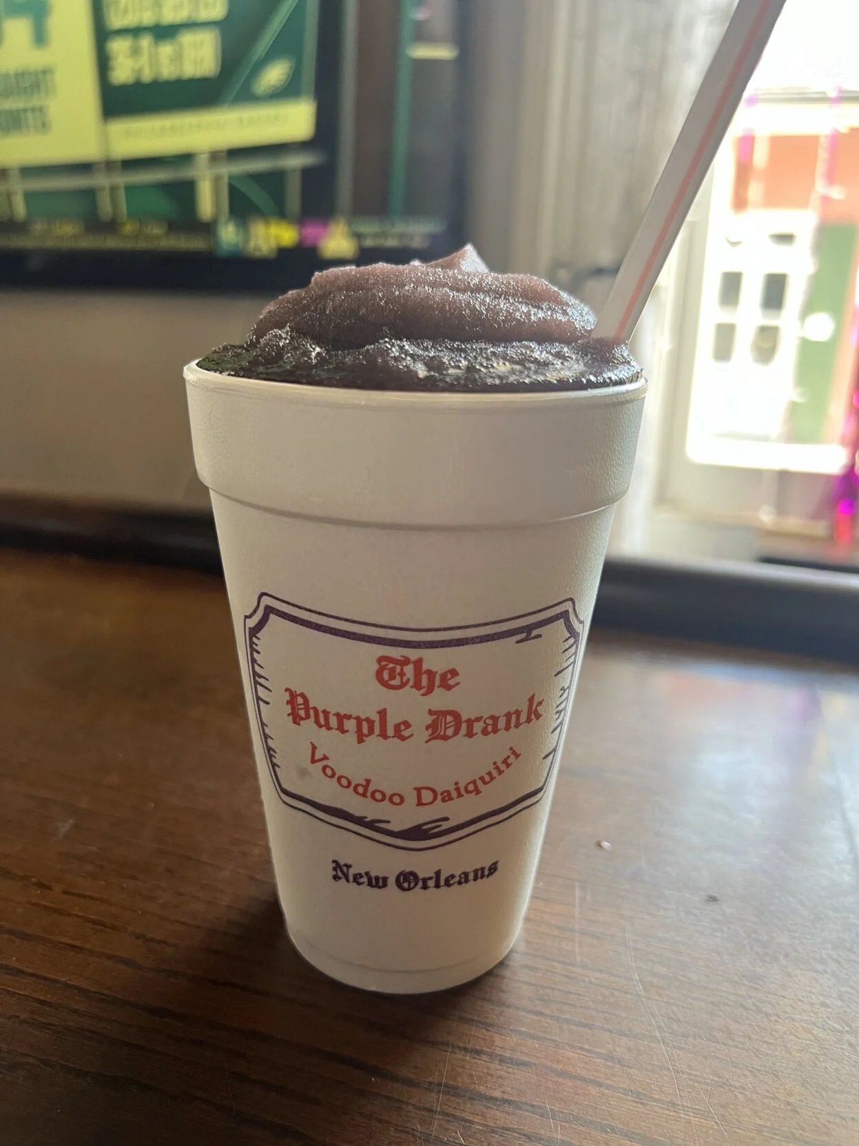 The Purple Drank Voodoo Daiquiri frozen purple in a branded New Orleans cup with a red and white straw